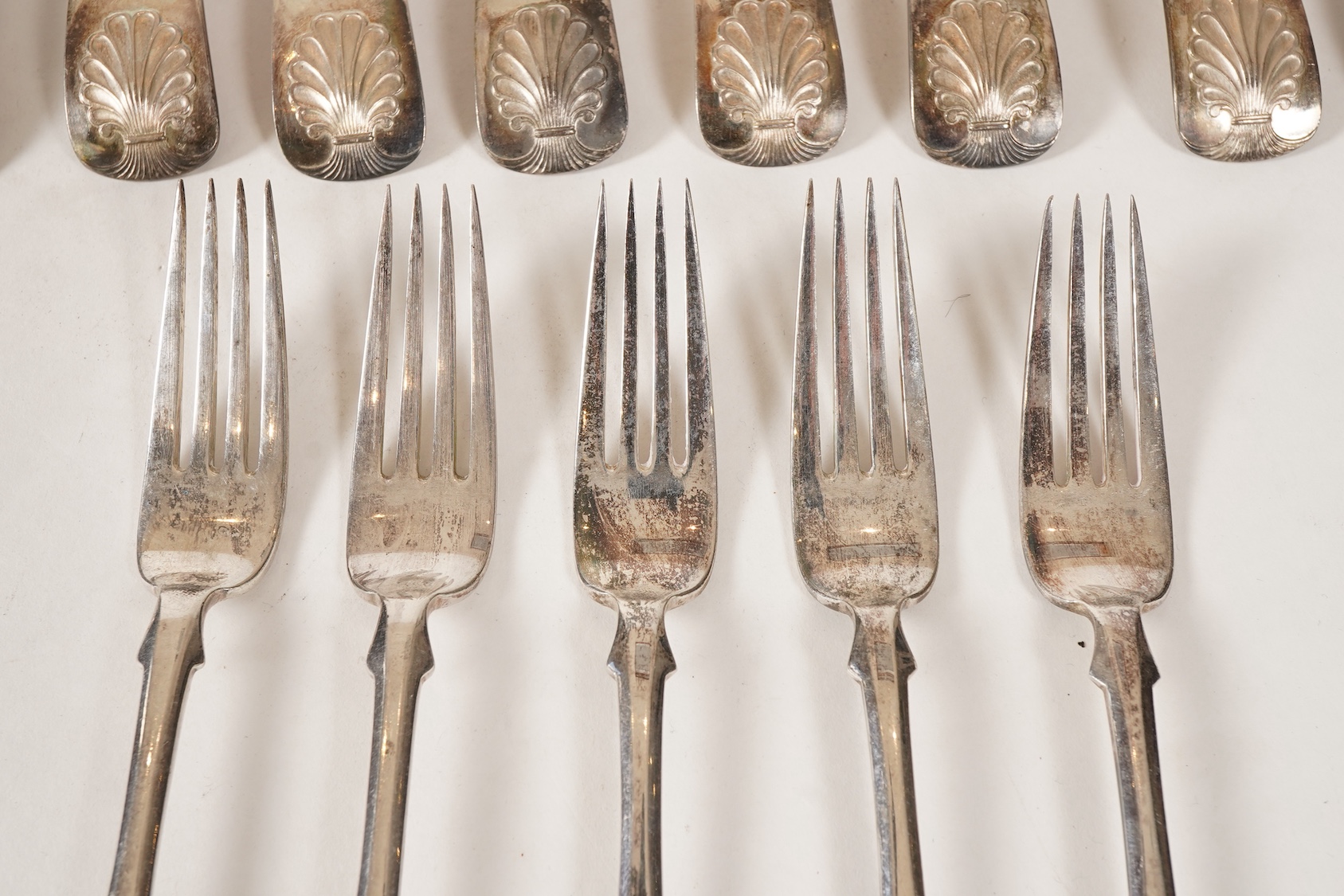 A set of twelve white metal fiddle and shell pattern table forks and five matching dessert forks